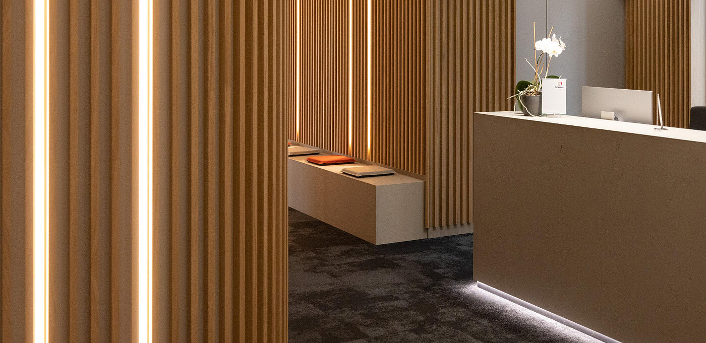 Moderne Empfangshalle mit Holzverkleidungen, sanfter Beleuchtung und minimalistischer Einrichtung, inkl. Pflanzen.