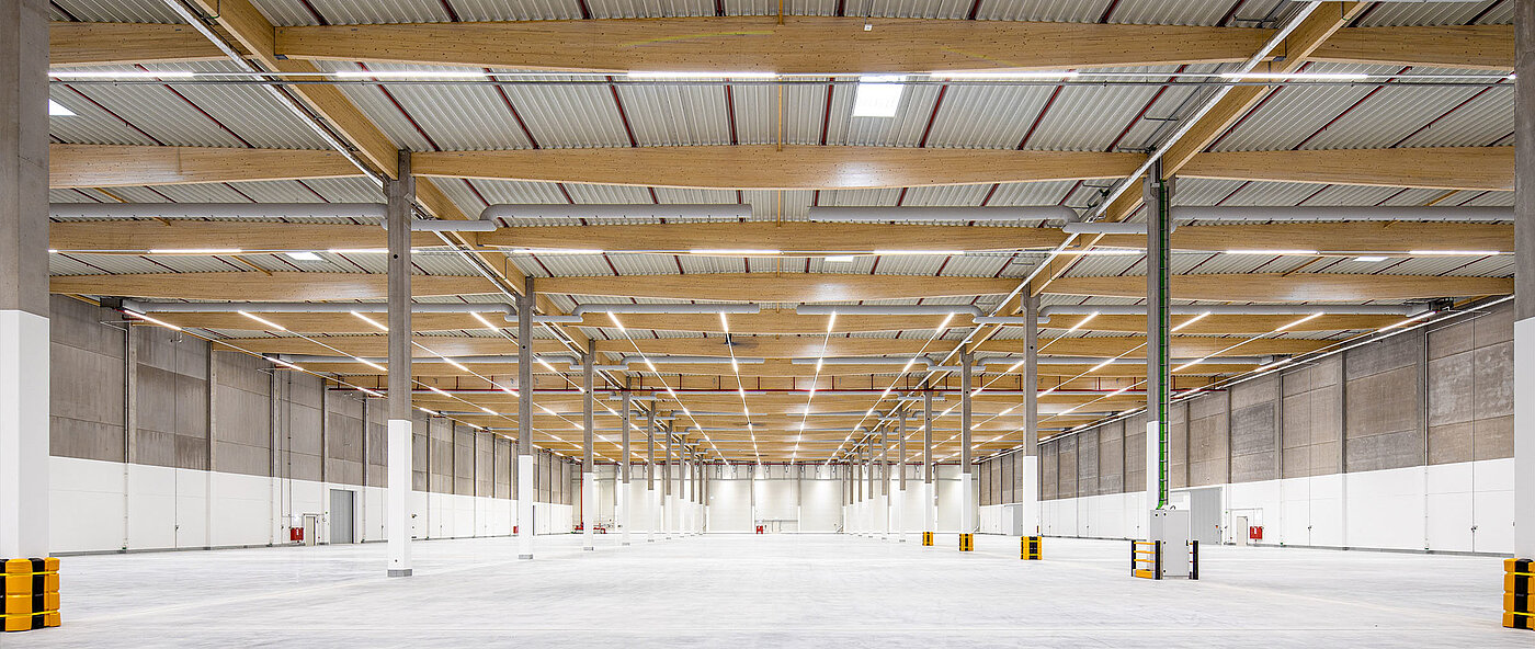 Spacious warehouse with tiled floor, high ceilings, and exposed wood and metal structures.