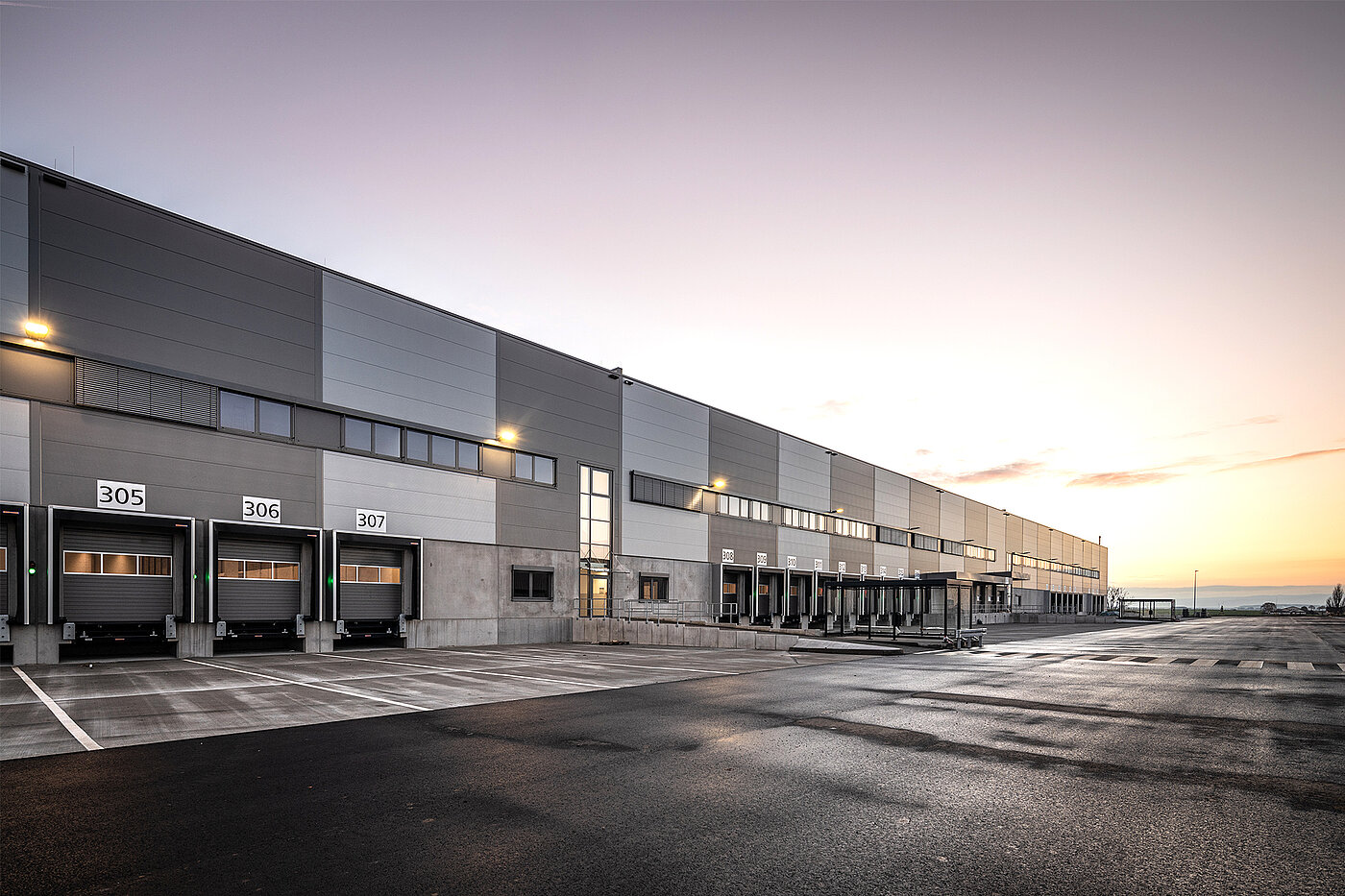 Blick auf die Nordseite des Logistikneubaus mit drei Tiefhöfen bei Sonnenuntergang