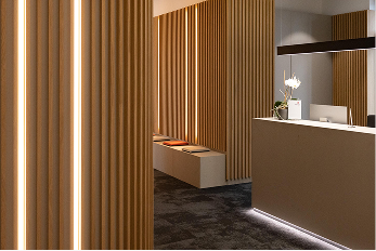 Moderne Empfangshalle mit Holzverkleidung, beleuchtetem Empfangstresen und Sitzgelegenheiten.