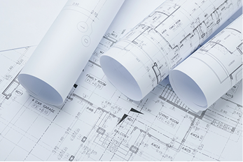 Drei gerollte Baupläne liegen auf einem Tisch, umgeben von technischen Zeichnungen.