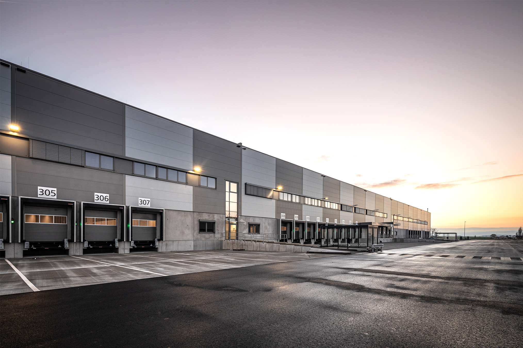 Blick auf die Nordseite des Logistikneubaus mit drei Tiefhöfen bei Sonnenuntergang