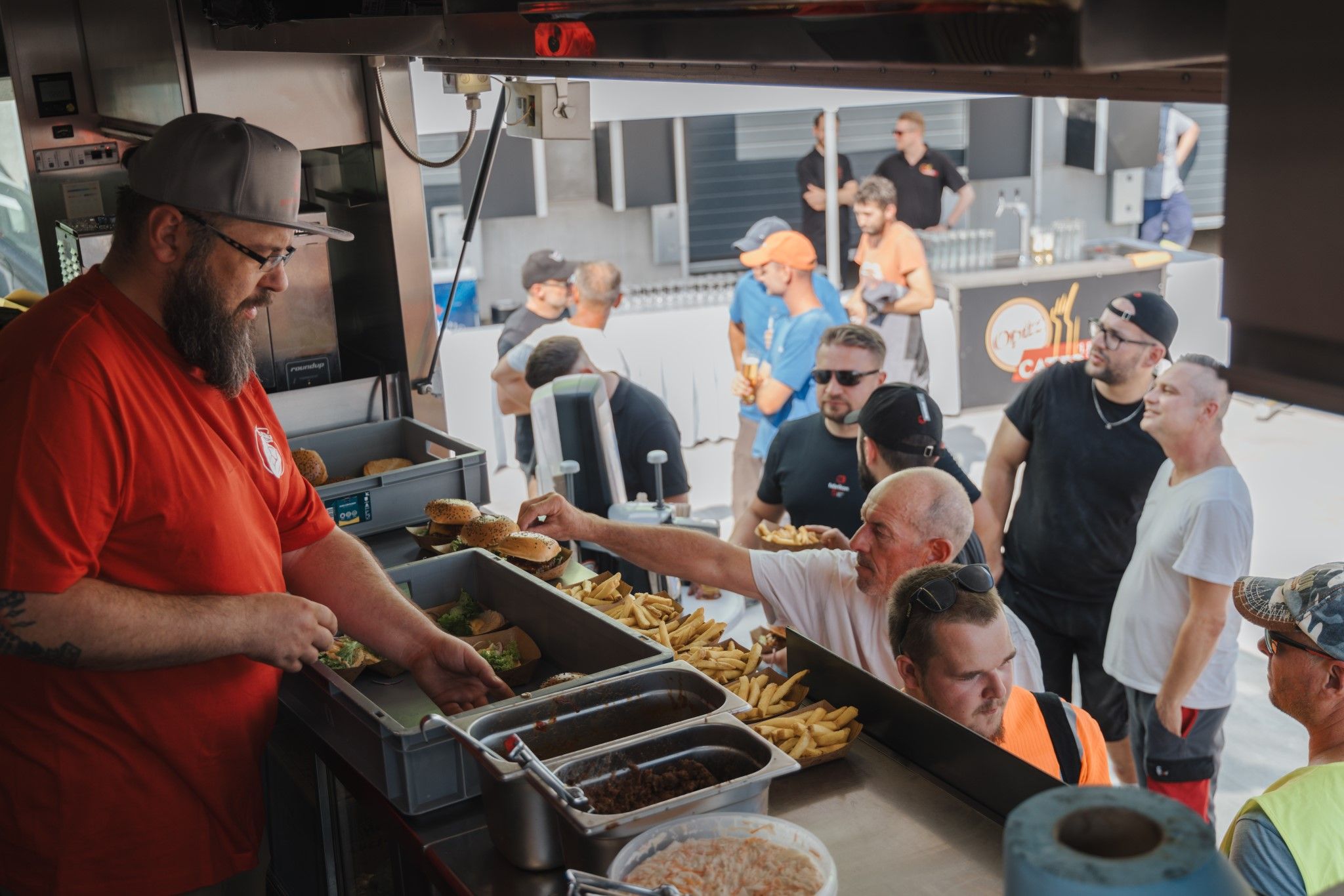 A salesperson in a food truck serves burgers and fries to waiting customers.