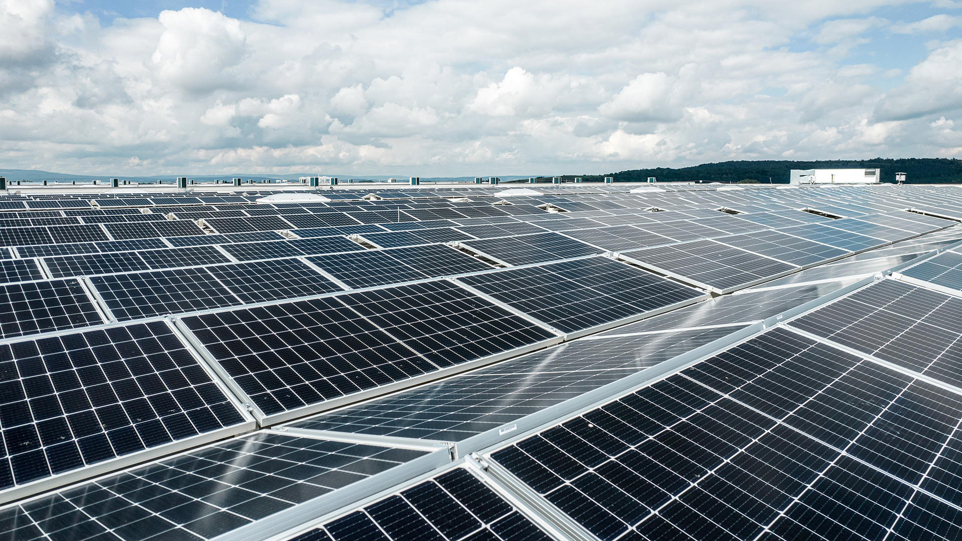 Solarpanel-Installation auf einem Dach, unter einem bewölkten Himmel.