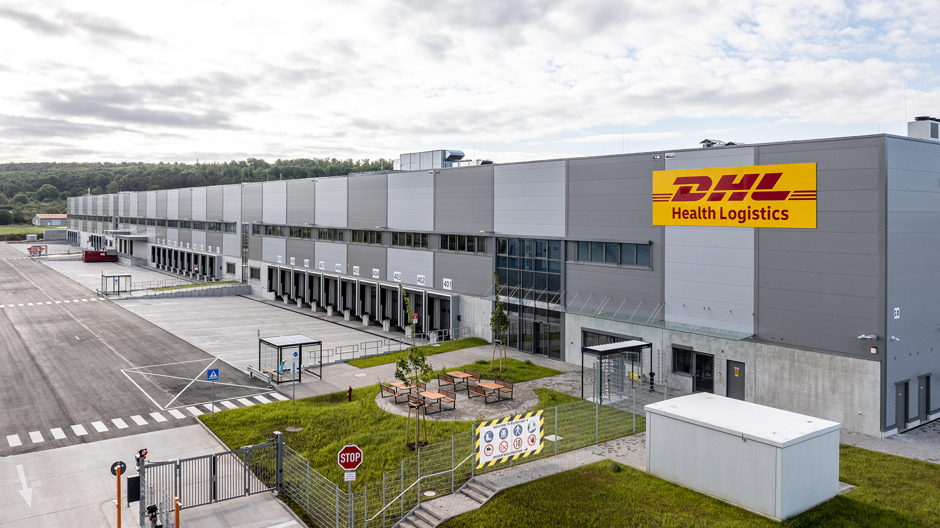 Luftaufnahme eines DHL Health Logistics Zentrums mit Parkplätzen und Laderampen.