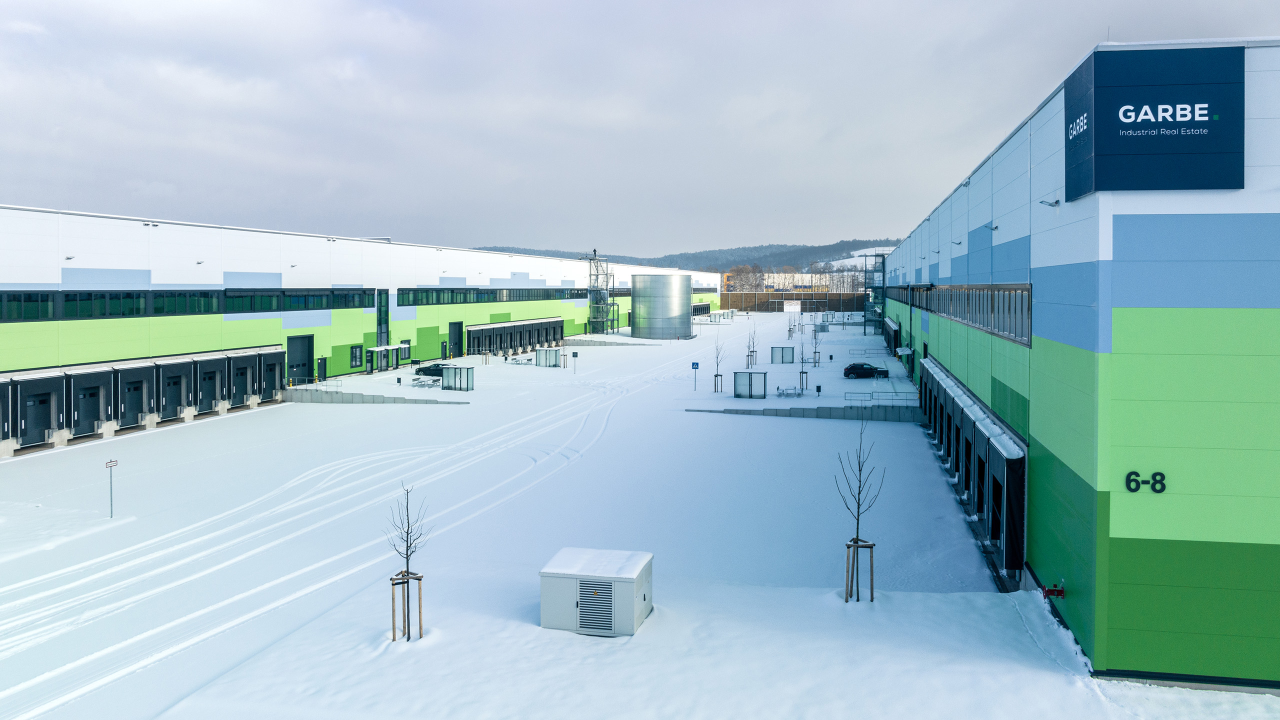 Moderne Lager- und Bürogebäude in einem gewerblichen Komplex, umgeben von frischem Schnee und grauem Himmel.