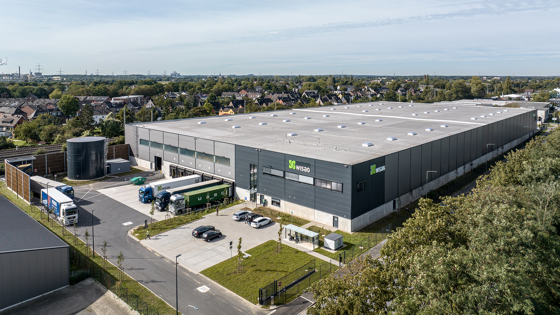 Großes Industriegebäude mit landwirtschaftlichem Bereich und Lkw-Parkplatz in städtischer Umgebung.