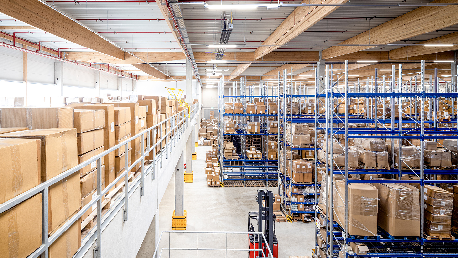 Lagerraum mit hohen Regalen, gefüllt mit Kartons, und einem Gabelstapler im Vordergrund. Helles, modernes Design.
