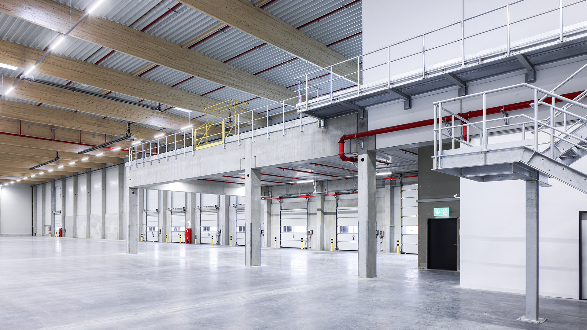 Großer, moderner Innenraum eines Lagerhauses mit hohen Decken, Betonsäulen und mehreren Laderampen.
