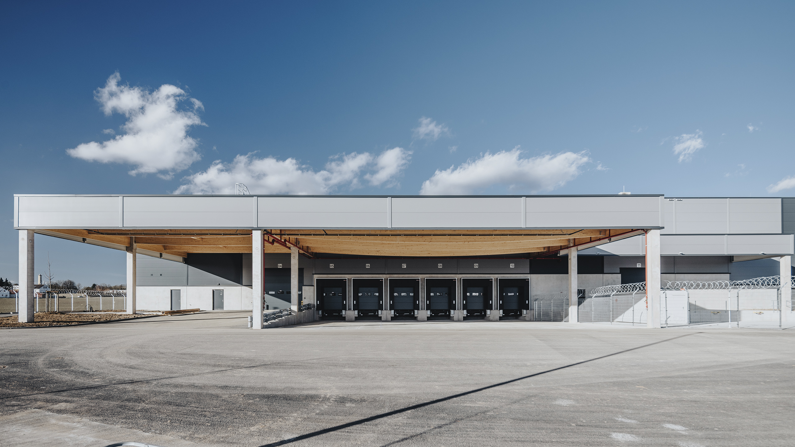 Lagergebäude mit überdachten Ladeplattformen und mehreren Lkw-Rampen unter einem klaren Himmel.
