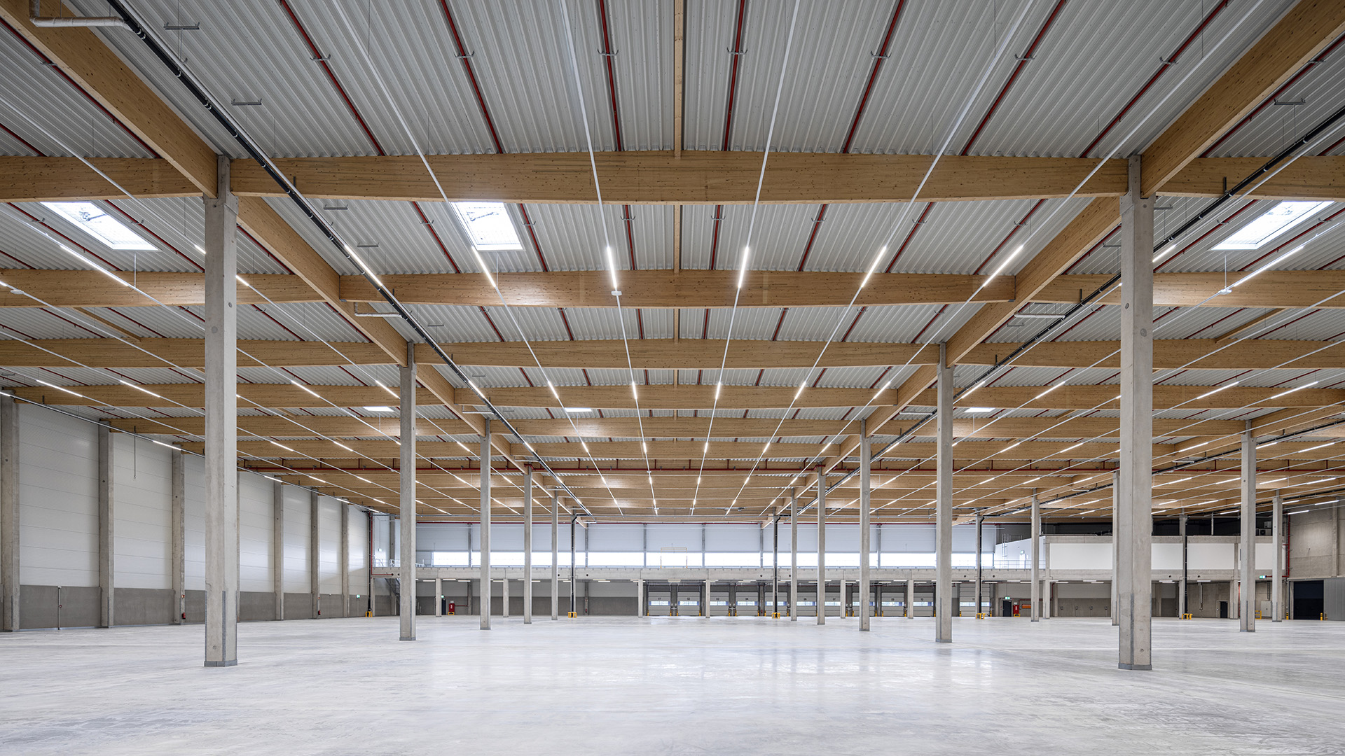 Logistikbauprojekt Hillwood Möckern - Innenansicht mit Holzbinder-Dachtragwerk und Hallenfläche - Blick auf die Lagermezzanine