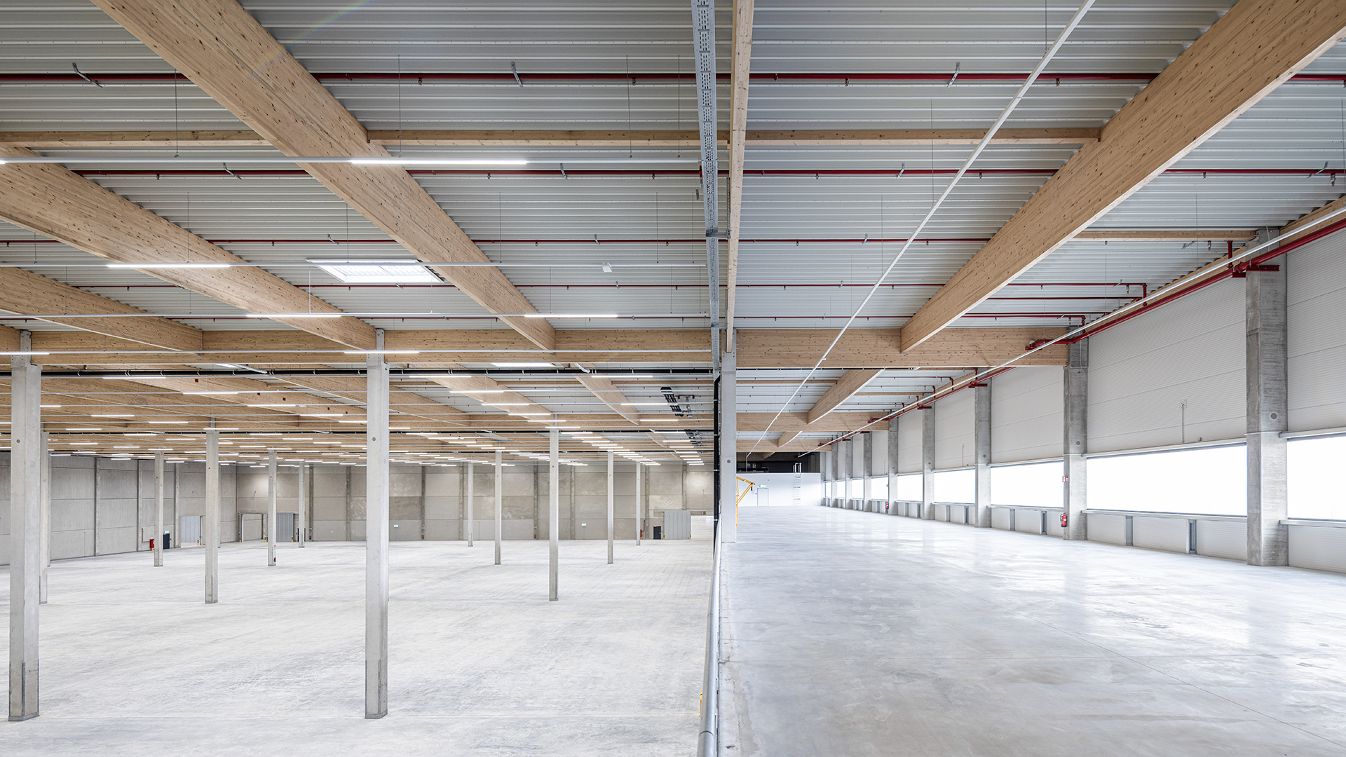 Logistikbauprojekt Hillwood Möckern - Innenansicht mit Holzbinder-Dachtragwerk und Hallenfläche - Blick von der Lagermezzanine in die Halle