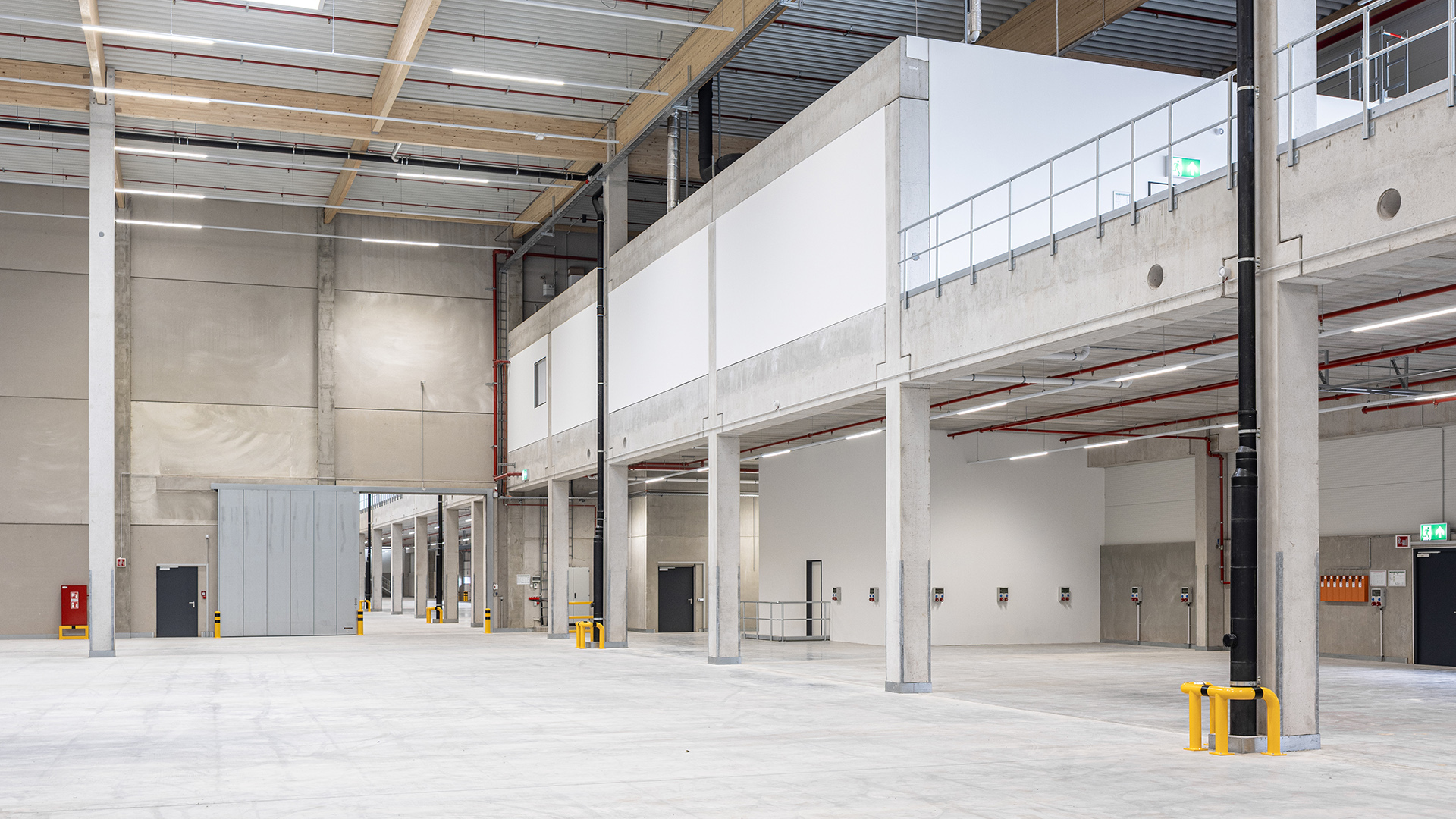 Logistikbauprojekt Hillwood Möckern - Innenansicht mit Holzbinder-Dachtragwerk und Hallenfläche - Blick auf die Mezzanine-Ebene